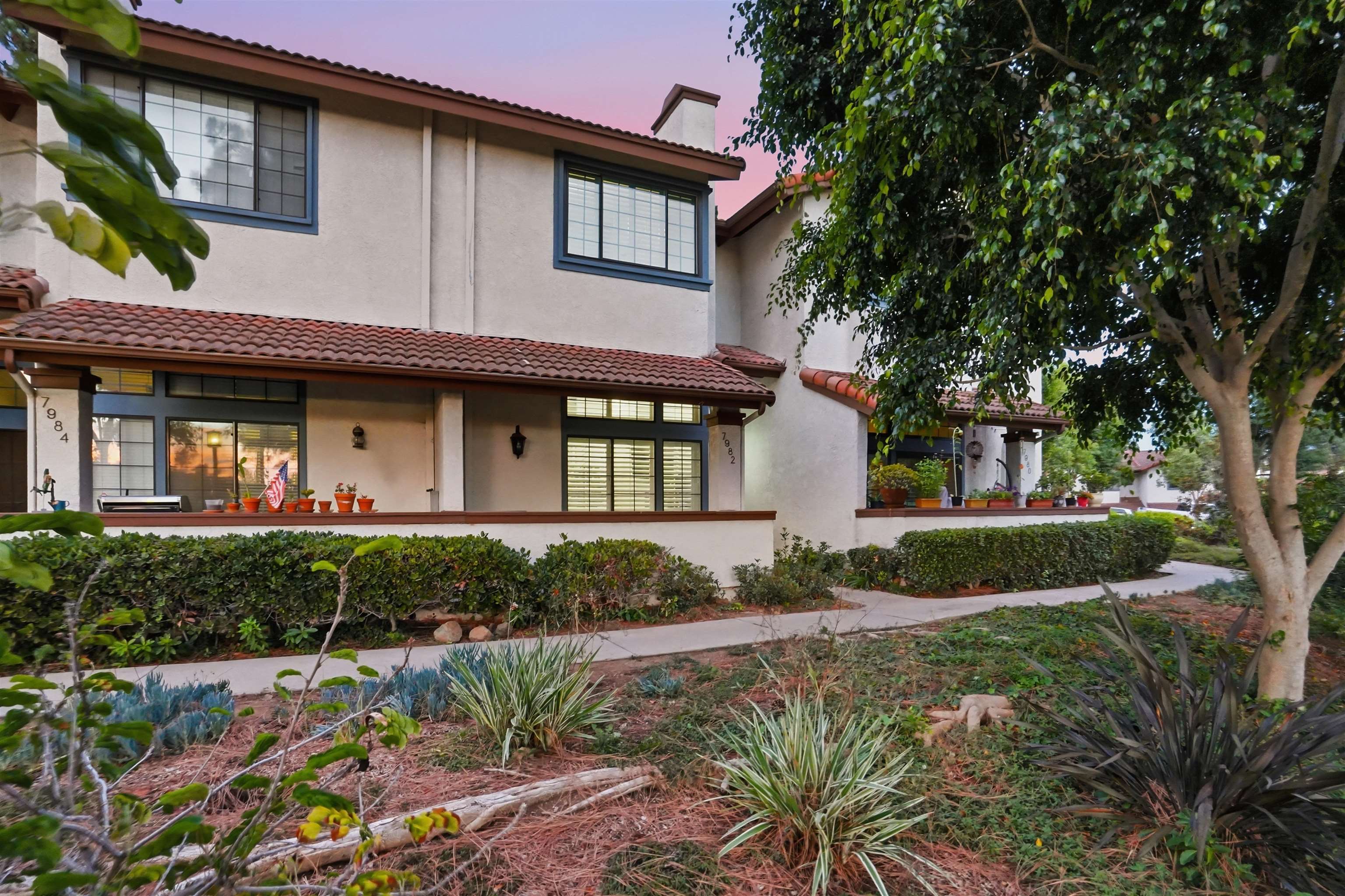Front elevation of 7982 Mission Vista at dusk, a tile-roofed townhome with a covered front porch in the Mariposa community of San Carlos