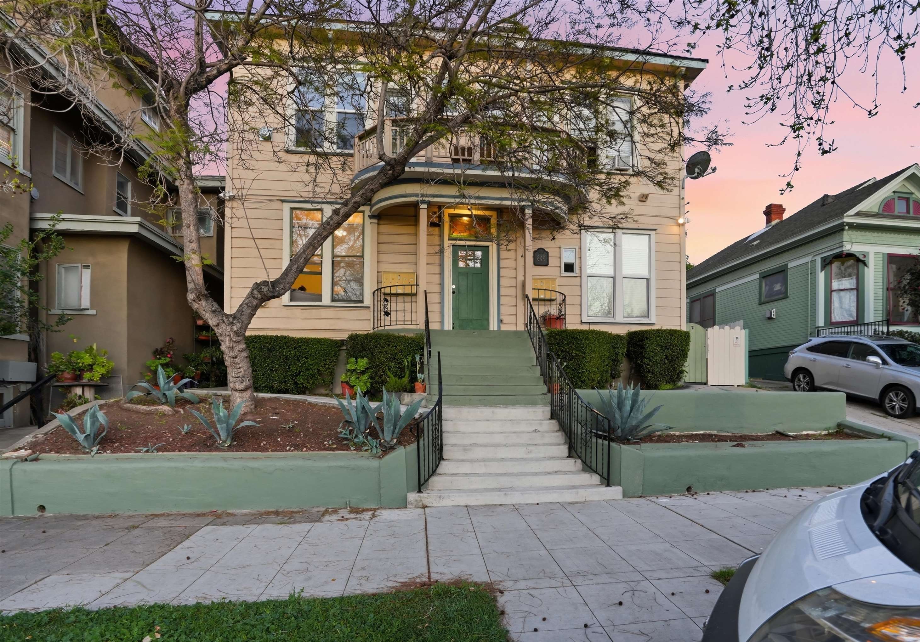Front elevation of 849 22nd St at dusk, a two-story historic eight-unit building in Golden Hill with a curved front porch and steps up from the sidewalk